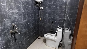 A bathroom with a toilet, a shower, and a marble wall. - Fabhotel Devi Residency (Vrindavan)