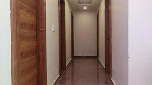 A hallway with wooden doors on either side and a tiled floor. - Fabhotel Devi Residency (Vrindavan)