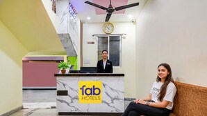 Ein Hotel-Empfangsbereich mit Marmor-Schalter, einer Uhr und einem Deckenventilator.