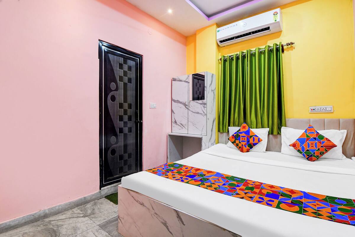 A bedroom with a bed, a wardrobe, an air conditioner, and a green curtain.