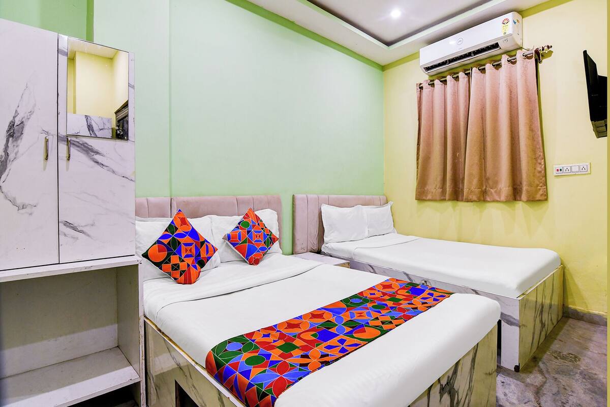 A hotel room with two beds, a marble cabinet, a green wall, and an air conditioning unit.