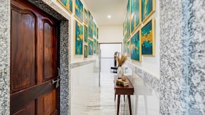 Un couloir avec une porte en bois, des murs en marbre et des œuvres d’art encadrées.