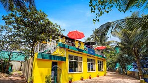 Un bâtiment jaune doté d’un balcon, de plantes en pot et de parasols.