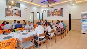 A restaurant with multiple tables and chairs, ceiling fans, and artwork on the walls. - Fabhotel Relax Inn (Shirur)