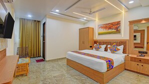 A hotel room with a bed, wooden wardrobe, bedside table, and a television mounted on the wall. - Fabhotel Relax Inn (Shirur)