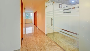 A hallway with a marble floor, glass doors, and a ceiling with recessed lighting. - Fabhotel Relax Inn (Shirur)