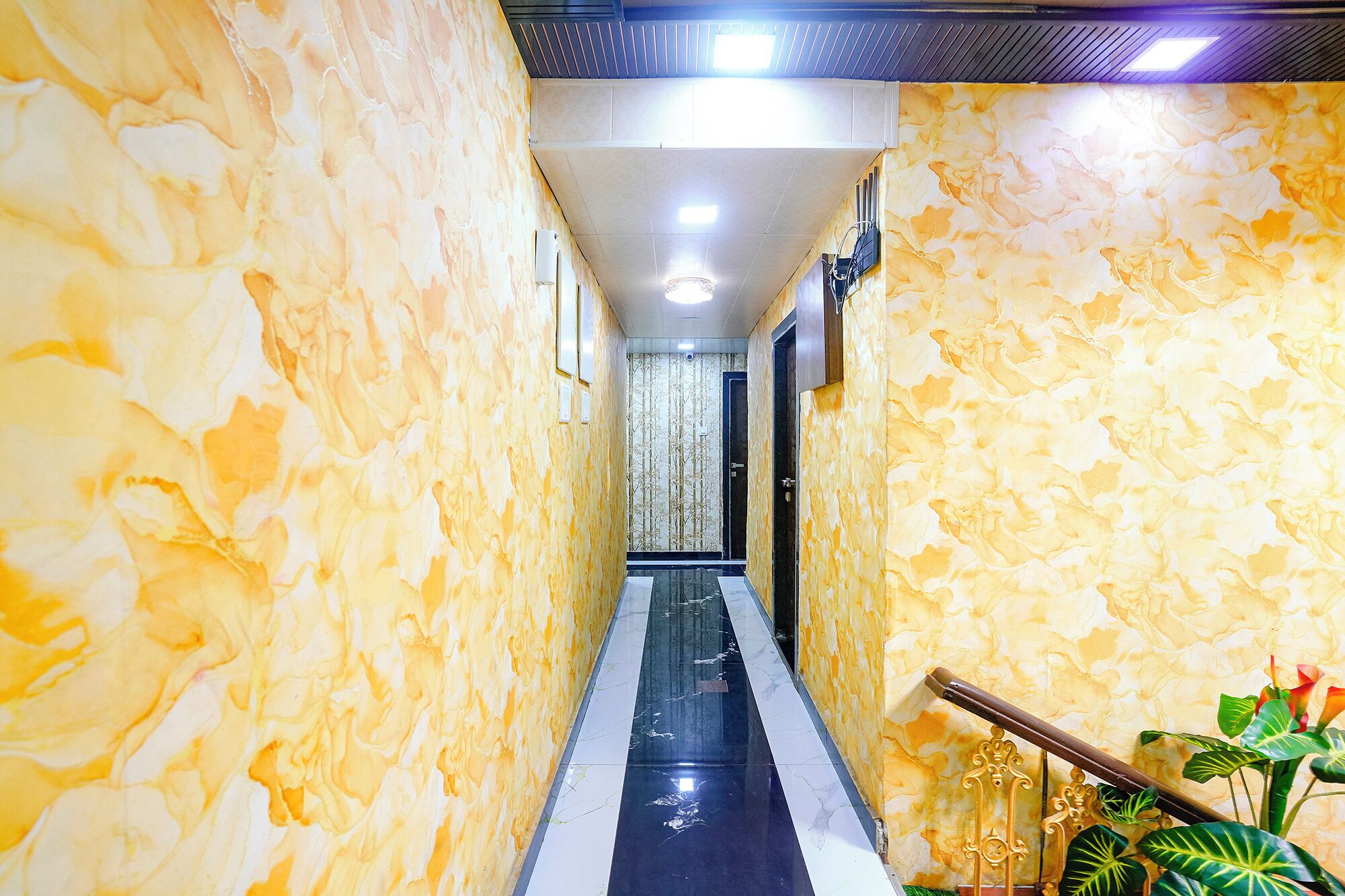 A hallway with marble walls and a reflective floor, leading to a door at the end.