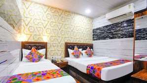 Habitación de hotel con dos camas, cabecero de madera, pared con diseño y un espejo grande.