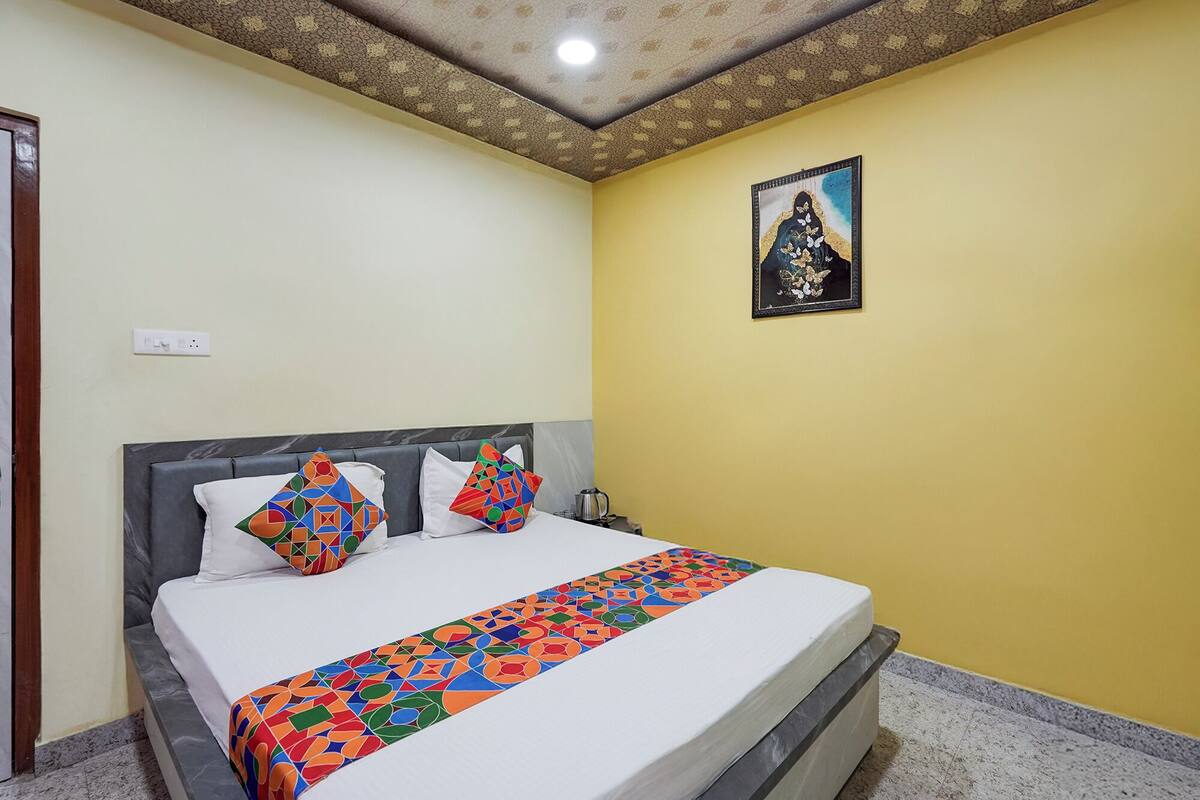 Un dormitorio con cama, almohadas, un cuadro en la pared y un techo con diseño decorativo.