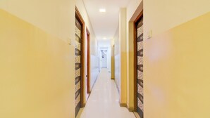 A long, narrow hallway with patterned doors on both sides, leading to a bright room at the end. - Fabhotel Devi Residency Wakad (Paud)