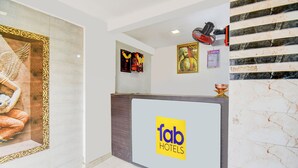 A hotel reception area with a marble wall, a reception desk, and a Buddha statue. - Fabhotel Galaxy Inn I (Pune)