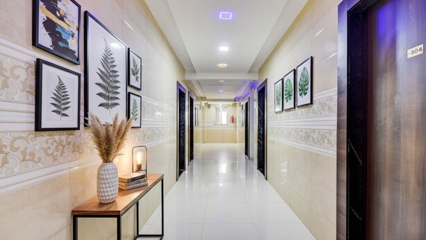 A hotel hallway with framed botanical prints on the walls, a console table with a vase and books, and a polished floor leading to a door marked with the number 304. - Fabhotel Galaxy Inn I (Pune)