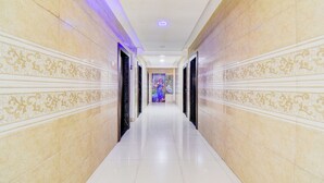 A hallway with marble walls and a tiled floor, leading to a room with a mural. - Fabhotel Galaxy Inn I (Pune)