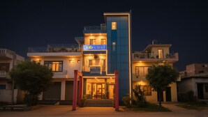 Un hotel moderno con un cartel llamativo, varios balcones y una entrada bien iluminada.