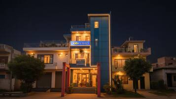 A modern hotel with a prominent sign, multiple balconies, and a well-lit entrance.