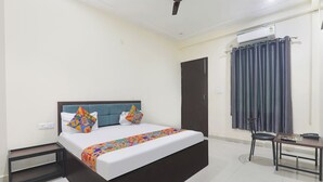 Un dormitorio ordenado con una cama, mesitas de noche, un escritorio y una silla.