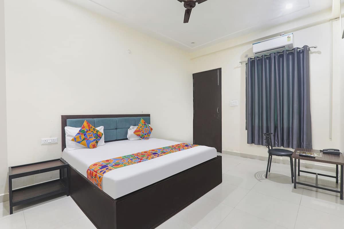A neatly arranged bedroom with a bed, bedside tables, a desk, and a chair.