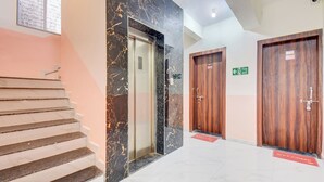 A hotel lobby with marble flooring, a staircase, and two wooden doors marked with room numbers. - Fabhotel Golden Eagle Executive (Paud)