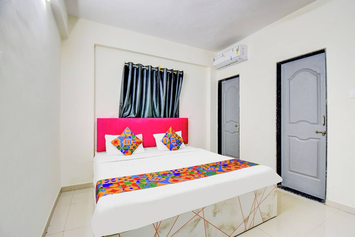 A bed with a colorful geometric-patterned bedspread, a pink headboard, and two decorative pillows.