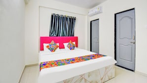 A bed with a colorful geometric-patterned bedspread, a pink headboard, and two decorative pillows. - Fabhotel Golden Eagle Executive (Paud)