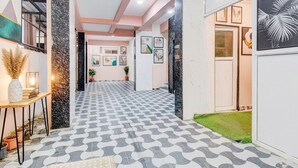 A hallway with patterned flooring, framed artwork on the walls, and a small table with decorative items. - Fabhotel Golden Eagle Executive (Paud)