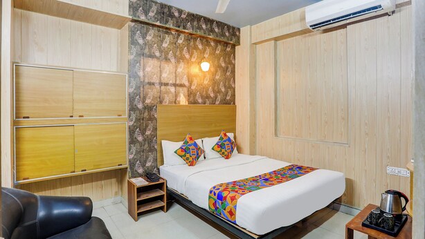 A hotel room with a bed, a desk, a chair, and an air conditioning unit. - Fabhotel Dream Inn (Danapur)