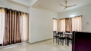 A spacious room with a dining area, a ceiling fan, and a refrigerator. - Fabhotel Ak Elite Luxury Homestay (Tirupati)