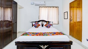 A bedroom with a bed, a wardrobe, a door, and an air conditioning unit. - Fabhotel Ak Elite Luxury Homestay (Tirupati)