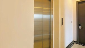 A hallway with a sliding glass door and a door with a keycard lock. - Fabhotel Vivek Inn (Prayagraj)