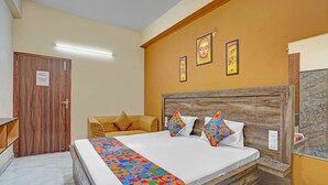 Une chambre d’hôtel avec une tête de lit en bois, un lit agrémenté d’oreillers aux motifs géométriques et aux couleurs vives, un comptoir d’accueil et une porte avec une pancarte.