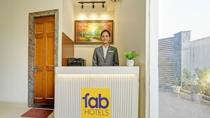 Un comptoir d’accueil orné du logo de « fab hotels », un réceptionniste, un tableau au-dessus du comptoir et une porte sur la gauche.