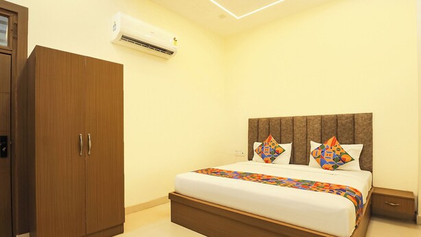 A hotel room with a bed, a wardrobe, and an air conditioning unit. - Fabhotel Lotus (Agra)