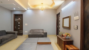 Una sala moderna con un sofá gris, un banco de madera y una pequeña mesa con flores.