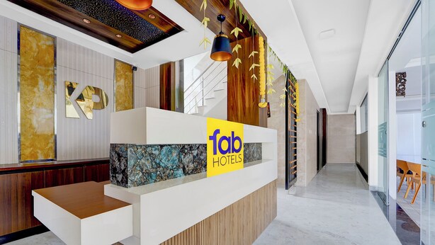 A modern hotel reception desk with a 'fab hotels' sign, a wooden accent wall, and a marble floor. - Fabhotel Kayal Plaza (Coimbatore)