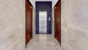 A marble-floored hallway with wooden doors and a central elevator. - Fabhotel Kayal Plaza (Coimbatore)