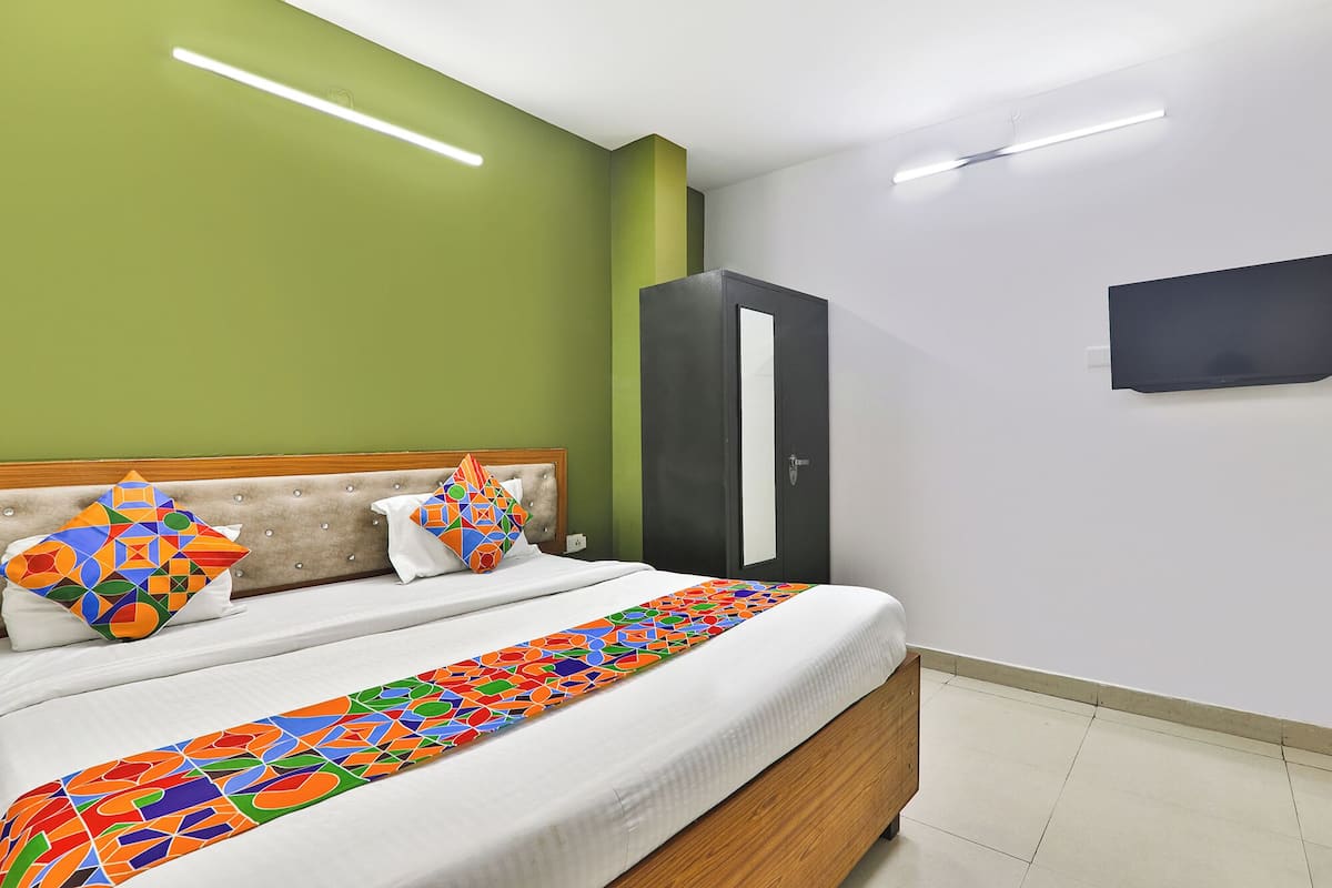 Ein Hotelzimmer mit einem Bett, grünen Wänden, einem Schrank und einem Flachbildfernseher.