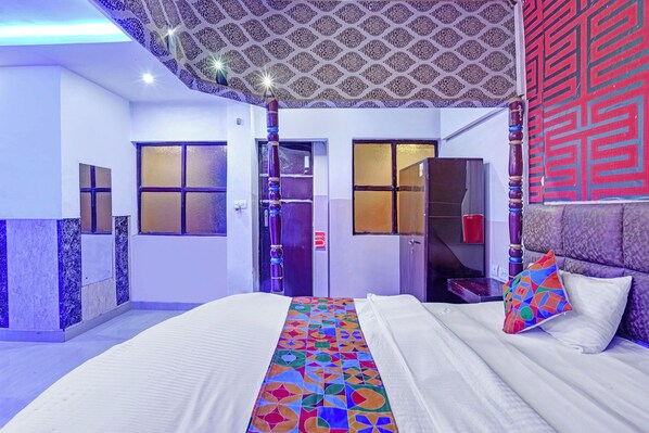 A hotel room with a bed, a colorful geometric-patterned bedspread, a red decorative wall panel, and a patterned ceiling. - Fabhotel D Season (Agra)