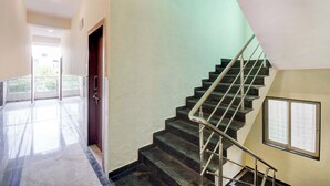 Μια σκάλα με μεταλλικά κάγκελα, θέα σε ένα μπαλκόνι και μια πόρτα που οδηγεί σε έναν εξωτερικό χώρο.