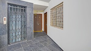A hallway with a metal gate, a wooden door, and a window with a grid pattern. - Fabhotel Ayaansh Himayatnagar (Hyderabad)