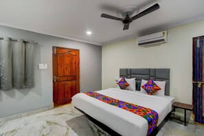 Une chambre à coucher avec un lit, un ventilateur de plafond, un climatiseur et une porte en bois.