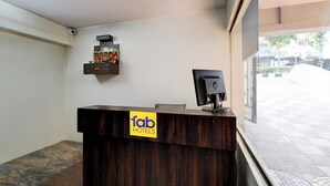 A reception desk with a sign for 'Tab Hotels', a computer monitor, and a decorative item on the wall.