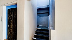A staircase with a blue handrail and a black door with a metal gate.