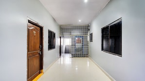 A hallway with a wooden door, a metal gate, and a window on the right.
