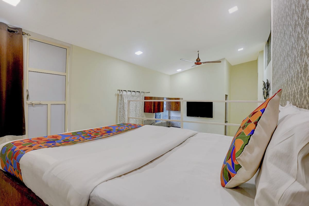 A hotel room with a large bed, a ceiling fan, a TV, and a wardrobe.