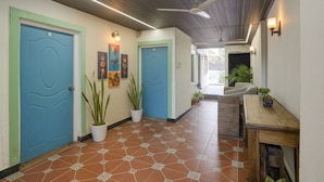 Un couloir avec des portes bleues, des plantes en pot et un banc en bois.