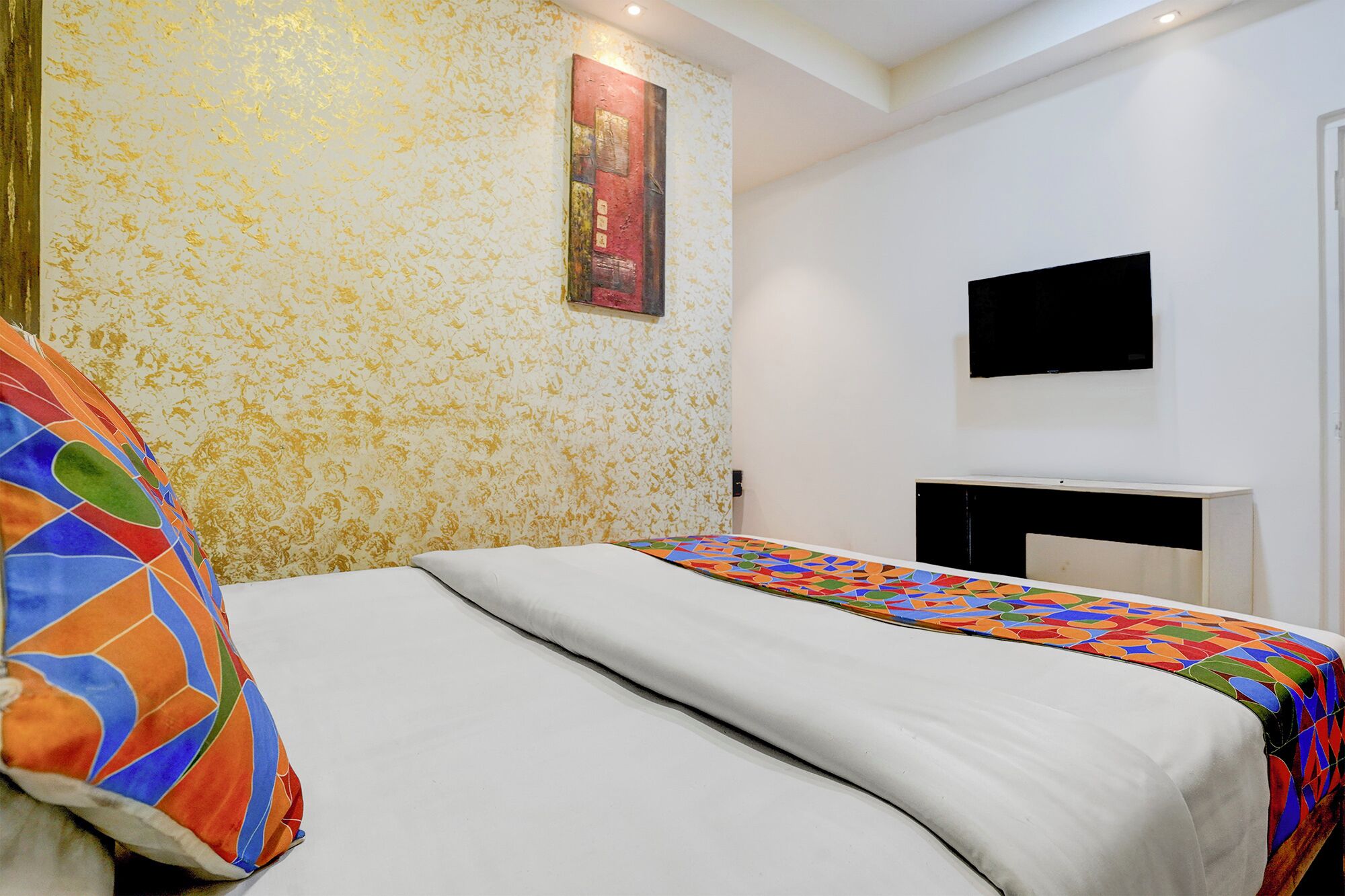 A bedroom with a bed, a TV mounted on the wall, and a fireplace.