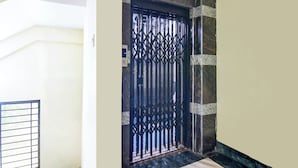 Ein schwarzes Metallgitter mit geometrischem Muster, eingebettet in eine Ecke mit einer Wand aus Marmoroptik und einem weißen Türrahmen.