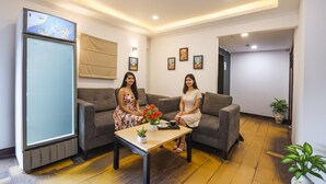 A modern hotel lobby with two sofas, a coffee table, and a refrigerator. - Fabhotel Crescent (Faridabad)