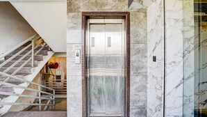 Ein Aufzug mit Marmorwand, einem Hinweisschild für ein Hotel und einer Treppe mit Metallgeländern.