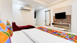 Ein modernes Hotelzimmer mit einem Bett, einem roten Sessel, einem an einer Steinwand befestigten Fernseher und einer Klimaanlage an der Decke.